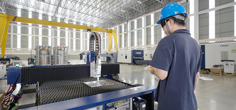 Technician operating an HSG Laser cutting machine in a modern industrial facility, showcasing precision laser cutting technology.