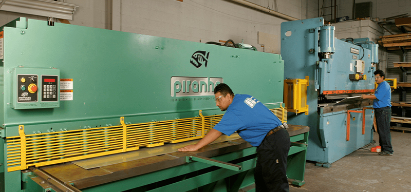 Workers operating Piranha metal fabrication machines, showcasing precision equipment for cutting, bending, and metalworking processes.